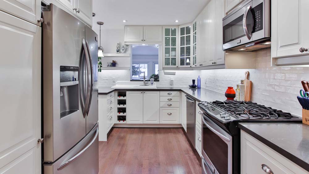 A clean, modern kitchen with white cabinets and stainless steel appliances